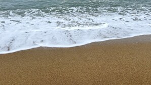 Una playa con arena y vista al océano bajo un cielo nublado.