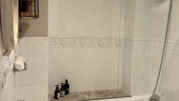 A bathroom with a bathtub, a sink, a mirror, and a shower.