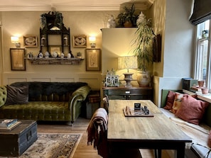 Un salón acogedor con un sofá verde, una mesa de centro de madera y un tablero de ajedrez.