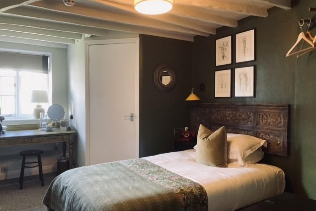 A bedroom with a bed, a dresser, a mirror, and framed artwork on the wall.