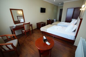 A hotel room with a wooden desk, two single beds, a chair, a small table with a tissue box, and a TV mounted on the wall. - Hotel 725 (Batumi)
