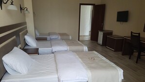Une chambre d’hôtel avec trois lits, un bureau, une chaise et un téléviseur.