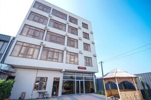 Un hotel de varios pisos con fachada plana, ventanas grandes y una entrada visible.