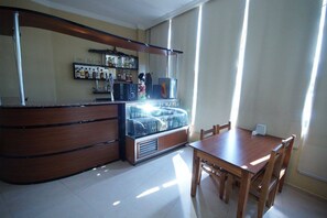 A restaurant with a wooden counter, a glass display case, and a dining area with a table and chairs. - Hotel 725 (Batumi)
