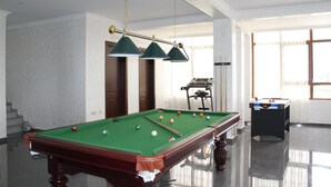 Une table de billard avec des billes, une queue de billard et une table de billard recouverte d’un drap vert.