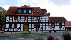 A traditional half-timbered building with a red-tiled roof, a central entrance with a wooden door, and multiple windows. - Landhotel zur Krone (Krayenberggemeinde)