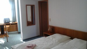 A hotel room with a bed, a desk, a chair, a television, and a mirror. - Landhotel zur Krone (Krayenberggemeinde)
