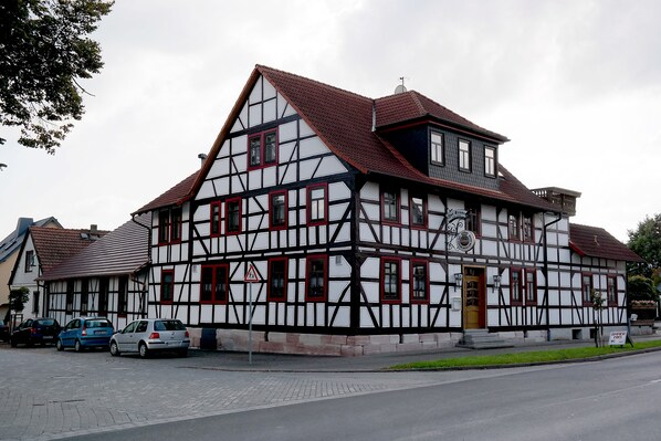 A traditional half-timbered building with a steeply pitched roof, multiple windows, and a visible entrance. - Landhotel zur Krone (Krayenberggemeinde)