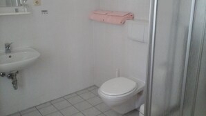 A small bathroom with a white sink, toilet, and a shower area. - Landhotel zur Krone (Krayenberggemeinde)