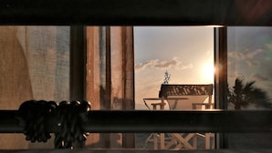 Une pièce avec une grande fenêtre, un banc en bois et une petite table.