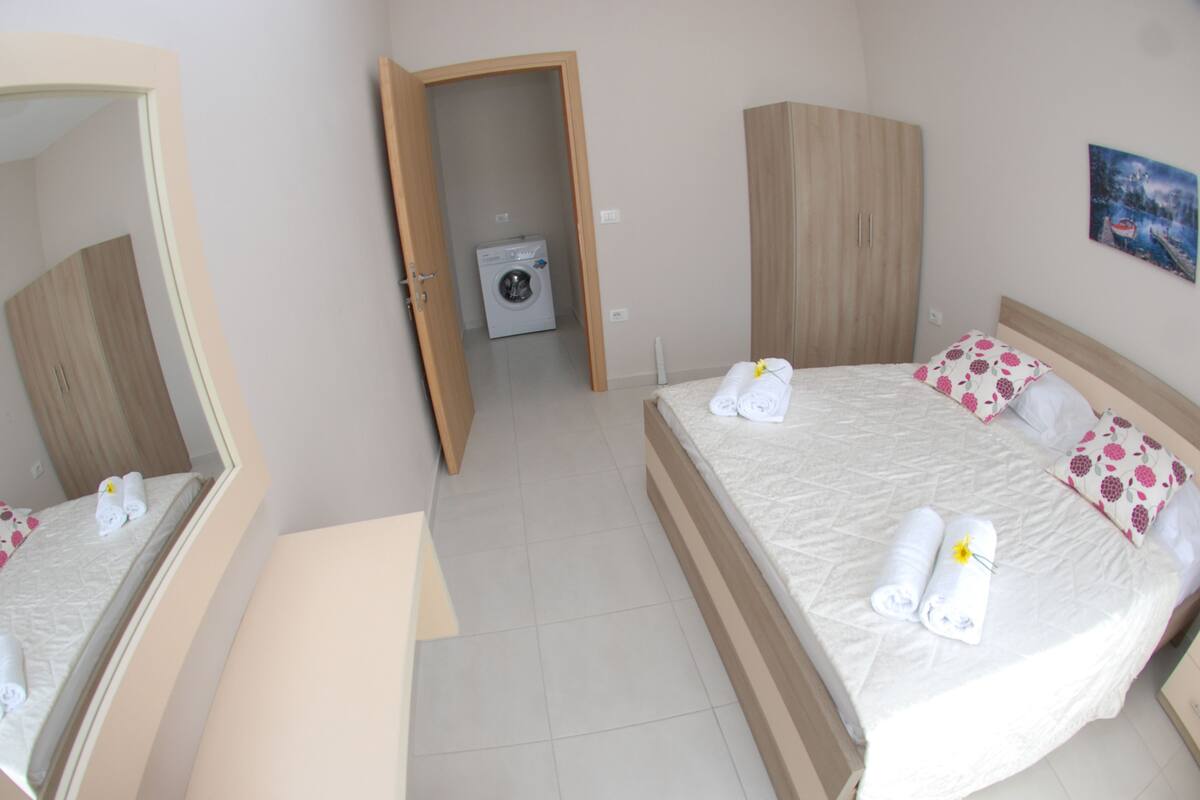 A hotel room with a bed, a desk, a wardrobe, and a washing machine.