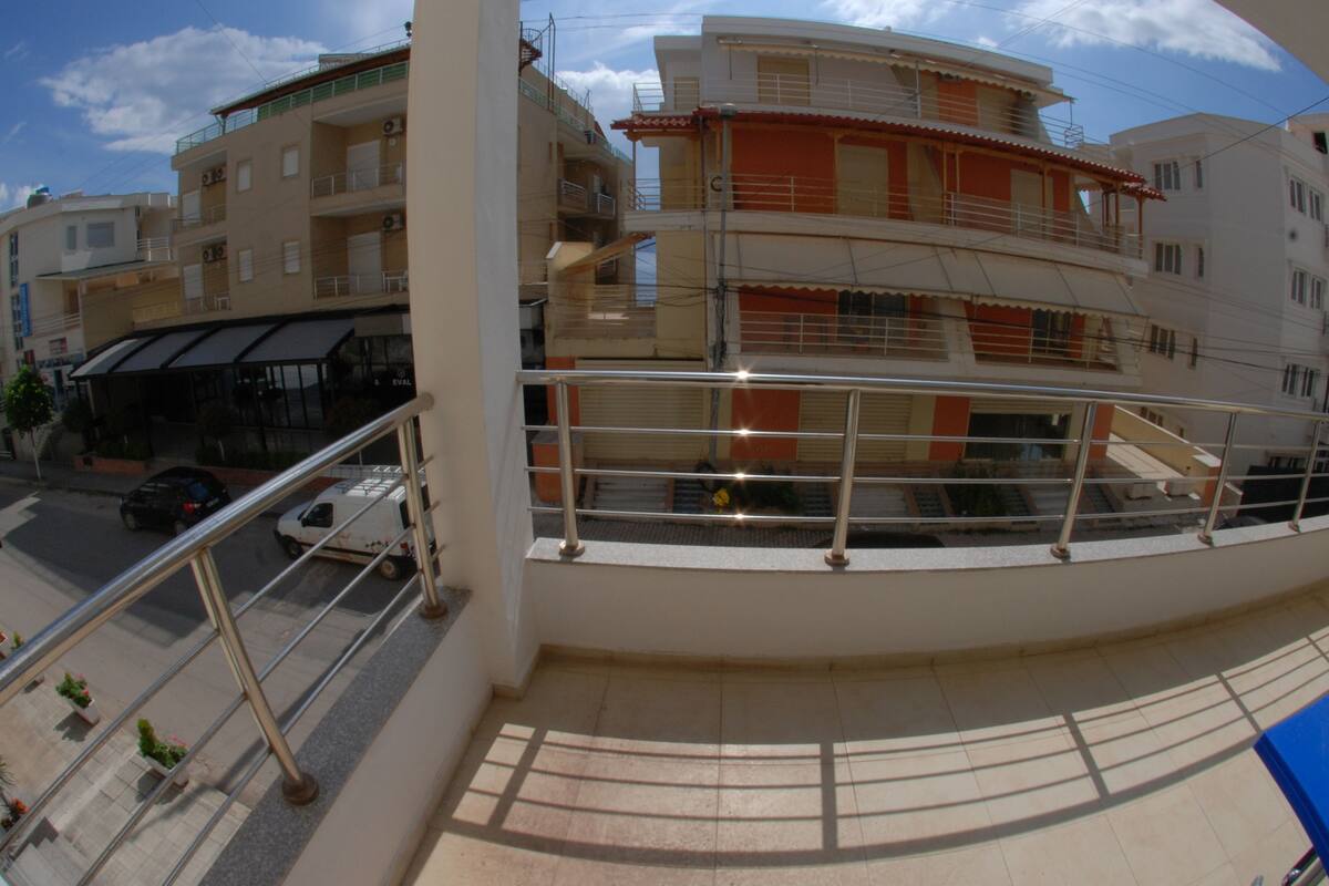 A multi-story building with balconies, a covered walkway, and a view of the street below.