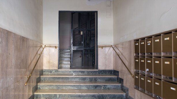A staircase with marble steps, metal handrails, and a metal door at the top. - Roma - Via la Spezia 70 (Rome)