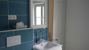 A bathroom with a white sink, a mirror, and blue tiles. - Chez Jules et Léonie (Valmondois)