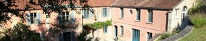 A row of traditional European-style buildings with uniform architecture, featuring shuttered windows and a consistent facade. - Chez Jules et Léonie (Valmondois)