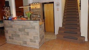A bar area with a wooden counter, a staircase, and a door with a sign. - Pension Sonneneck (Osterode am Harz)