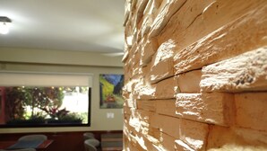 A room with a stone wall, wooden furniture, and a window with a view of greenery. - Hotel Haedo (Haedo)