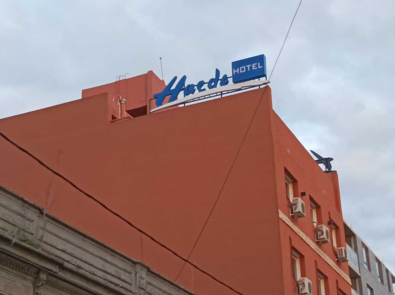 A hotel sign with the name "Harcros" and a "HOTEL" label on a red building.