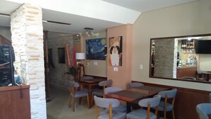 A dining area with a stone pillar, a painting, and a bar area with bottles. - Hotel Haedo (Haedo)