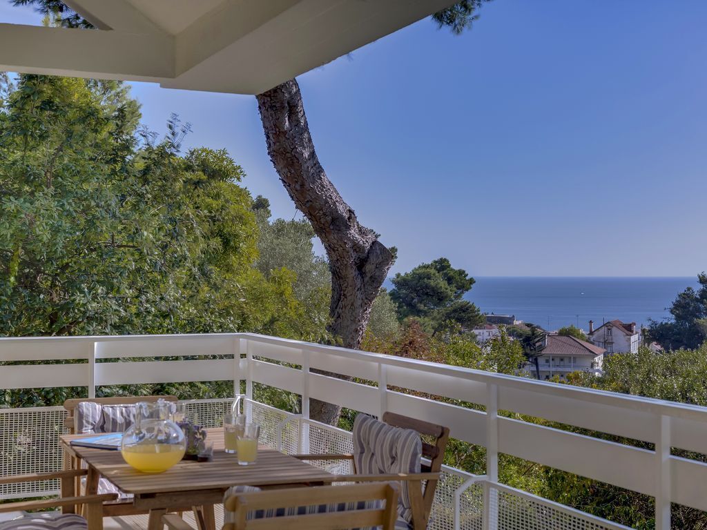 Un balcon avec une table dressée pour deux personnes, offrant une vue sur la côte.