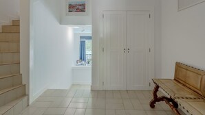 En hall med en trappa, en vit garderob och en bänk.