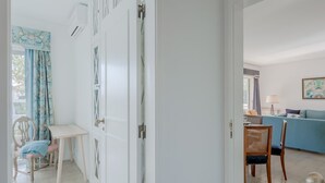 Ett rum med en vit dörr, ett matbord med stolar, en blå soffa och ett fönster med gardiner.