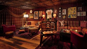 A cozy, vintage-themed living room with plaid decor, a fireplace, and a variety of framed pictures and memorabilia. - Graduate by Hilton Knoxville (Knoxville)