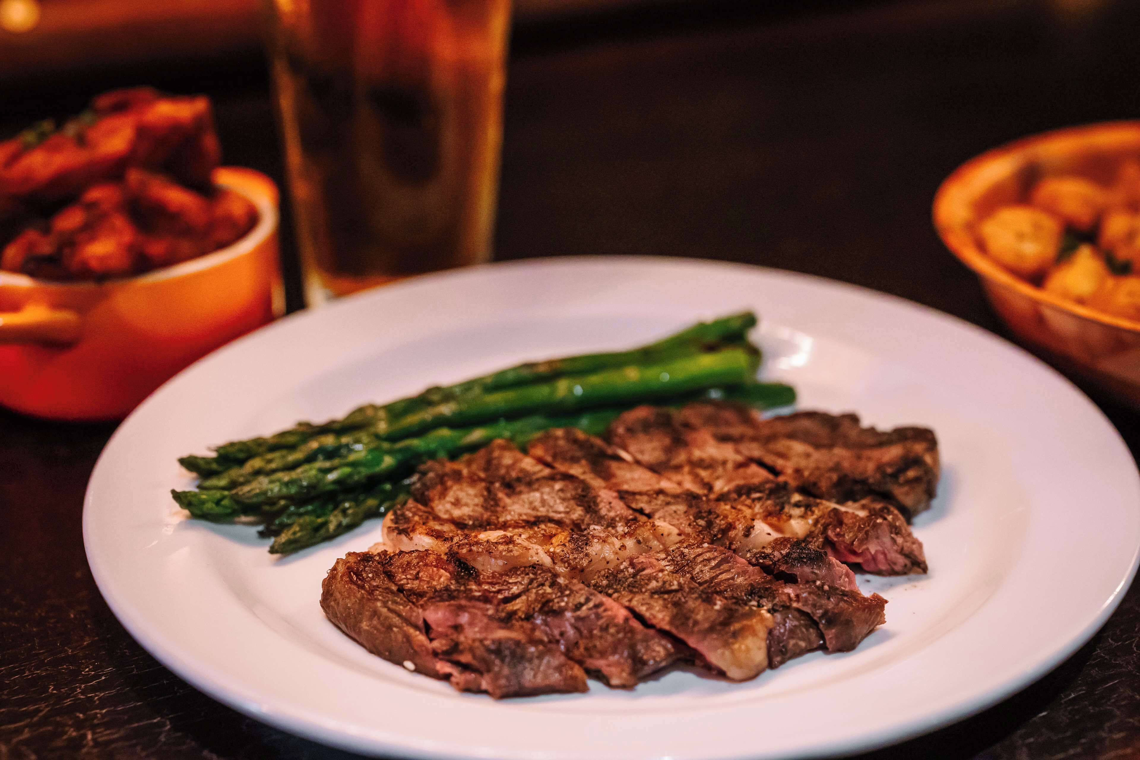 A plate with steak and asparagus on a table.