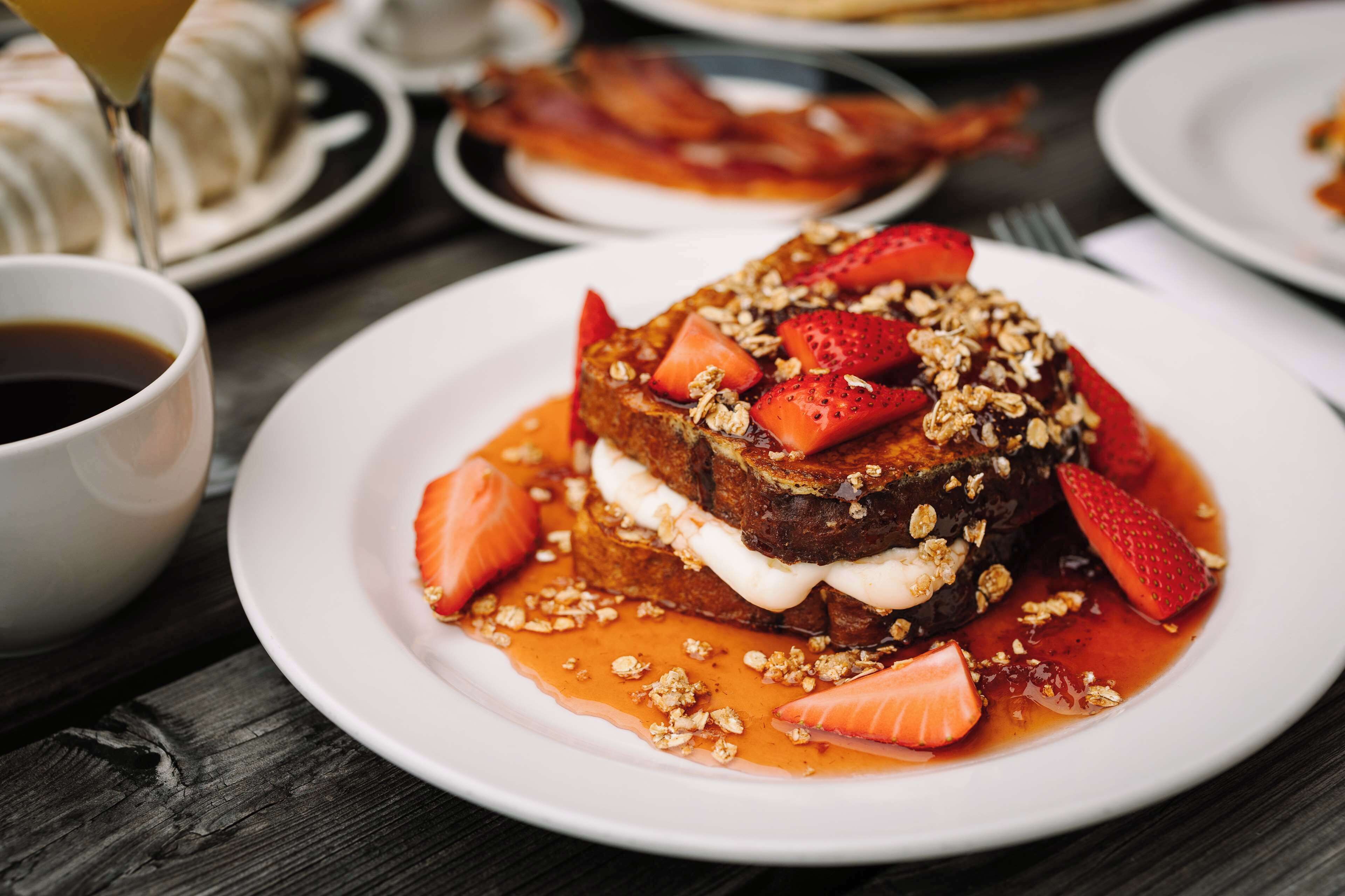 Un plato de desayuno con tostadas, fresas y granola.