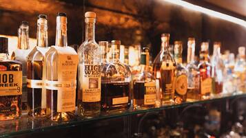 A variety of liquor bottles on a shelf in a bar setting.