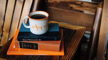 A stack of books with a coffee mug on top, placed on a wooden table.