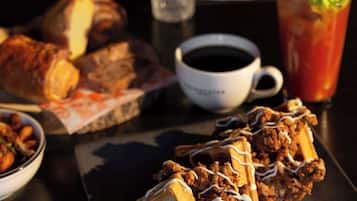 A meal with waffles, fried chicken, and a drink on a table.