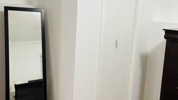 A room with a white door, a black dresser, and a mirror on the floor.