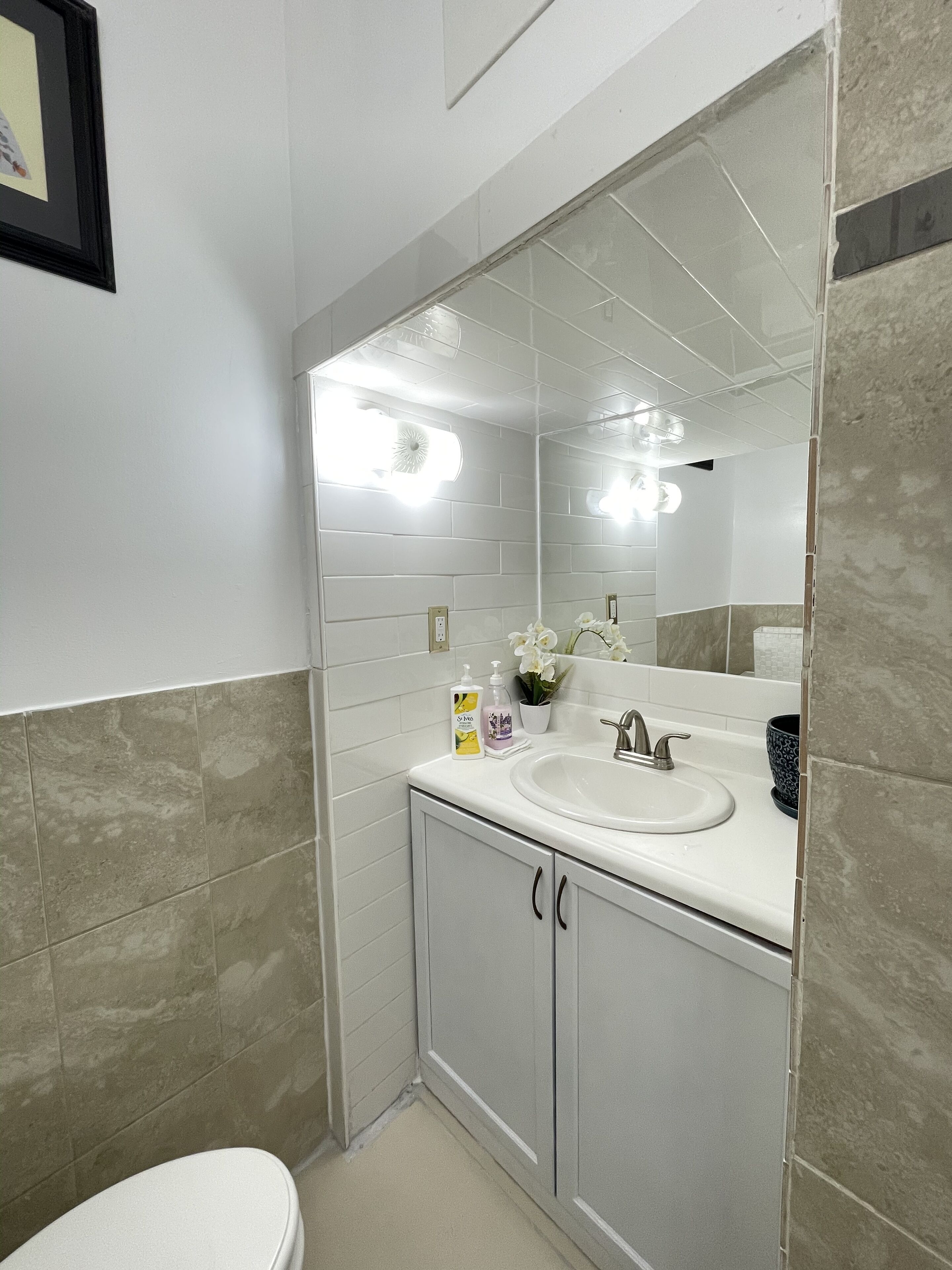 Une salle de bain avec un lavabo blanc, un miroir et des toilettes.