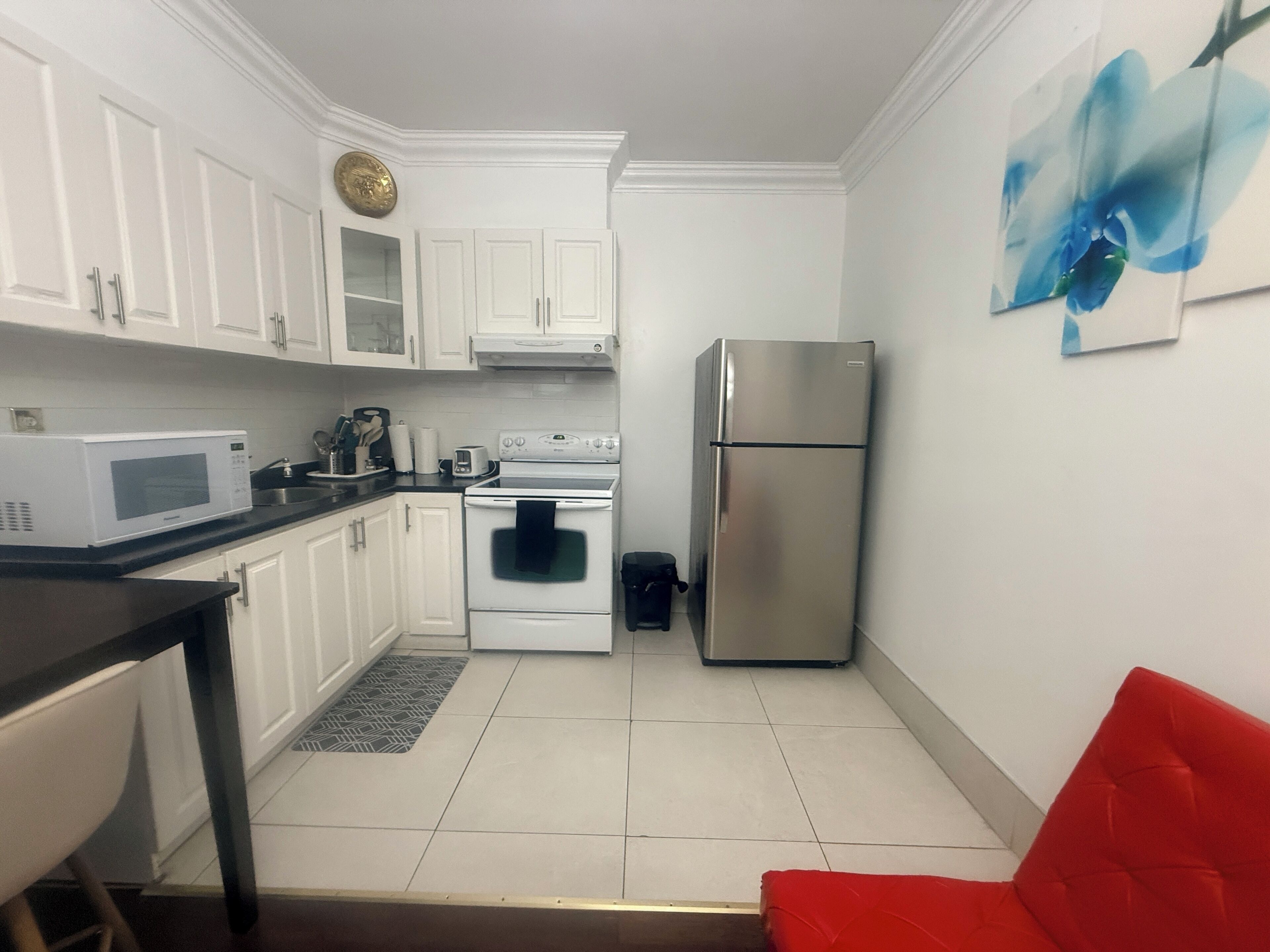 A compact kitchen with white cabinets, a microwave, an oven, and a refrigerator.
