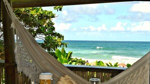 A hammock overlooking a beach with a table set for breakfast, including a teapot, cups, and a glass. - Pousada Shangri-lá (Itacaré)