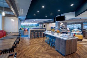 A modern restaurant with a long communal table, a bar area, and a counter with stools.