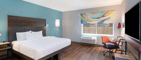 Une chambre d’hôtel moderne équipée d’un grand lit, d’un bureau, d’une chaise et d’un téléviseur.