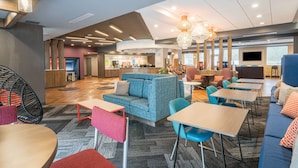 A modern hotel lobby with seating areas, a reception desk, and a TV screen. - Tru by Hilton Knoxville North I75 (Knoxville)
