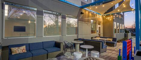 An outdoor seating area with a blue sofa, wicker chairs, and a round table.