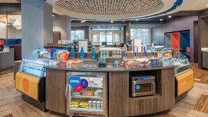 A self-service beverage station with a refrigerated display, a coffee machine, and a variety of snacks and drinks. - Tru by Hilton Knoxville North I75 (Knoxville)