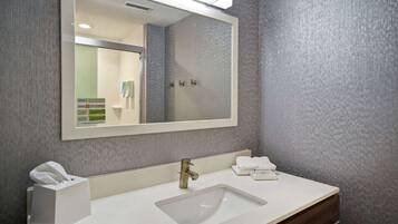 A bathroom with a large mirror, a sink, and a towel dispenser.