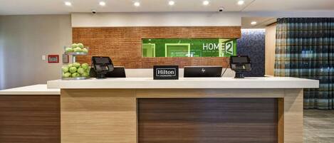 A hotel reception desk with a wooden counter, two black phones, and a sign that reads "Hilton Honors".