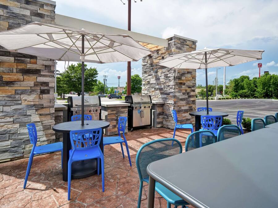 Une terrasse extérieure avec des murs en pierre, des chaises bleues et un barbecue.