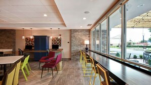 A restaurant with a long counter, multiple seating areas, and a view of the outside. - Home2 Suites by Hilton Georgetown (Georgetown)
