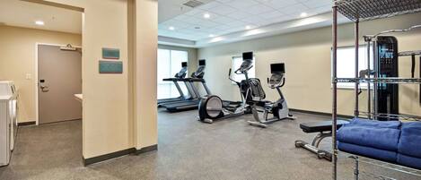 A gym with treadmills, elliptical machines, and a weight bench.