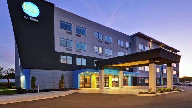 A modern hotel with a prominent 'tru by Hilton' sign, a covered entrance, and a well-lit facade. - Tru by Hilton Huber Heights (Dayton)