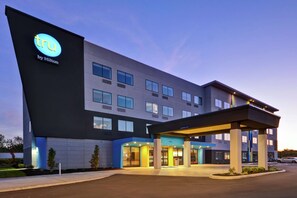 A modern hotel with a prominent 'tru by Hilton' sign, a covered entrance, and a well-lit facade. - Tru by Hilton Huber Heights (Dayton)