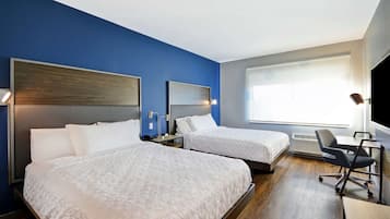 A hotel room with two beds, a desk, and a chair.