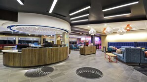 A modern hotel lobby with a reception desk, seating area, and decorative lighting. - Tru by Hilton Huber Heights (Dayton)